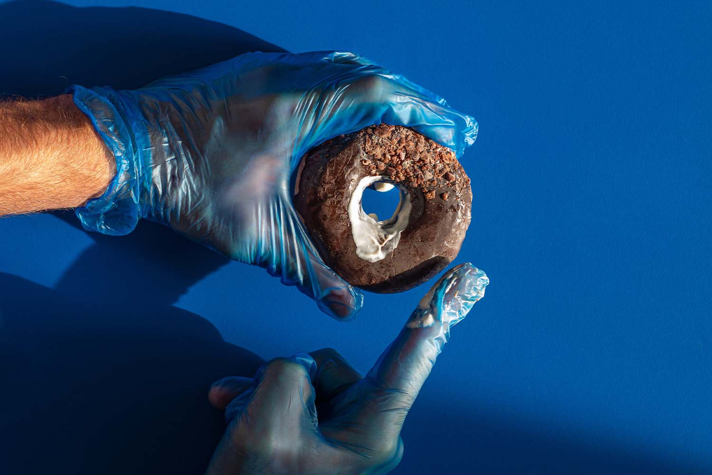 Man holding a chocolate donut that represents a rectum
